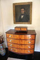 Bow-front chest of drawers under portrait at Jeremiah Lee Mansion. Marblehead, MA.