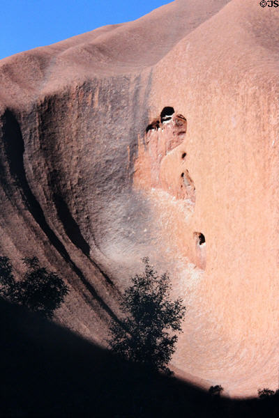 Caves dot smooth formations of Uluru (aka Ayers Rock). Australia.