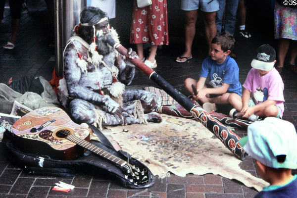 Aboriginal street entertainer plays his didgeridoo for a crowd. Sydney, Australia.