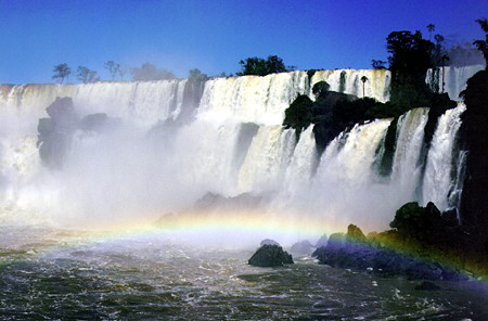 Rainbow forms in the mist of two levels of Iguaçu Falls. Brazil.