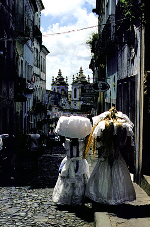 Two women in regional dress carrying cloth through the streets of Salvador. Brazil.