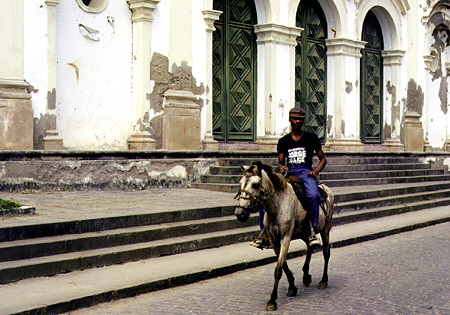 Donkey rider in front of Cachoeira village church. Brazil.