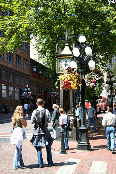 Visitors listen to whistles of Gastown Steam Clock. Vancouver, BC.