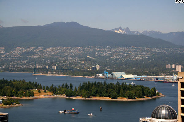 Stanley Park jutting in Vancouver harbour surrounded by mountains seen from above. Vancouver, BC.
