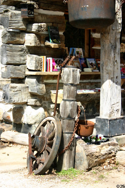 Wagon wheel leaning against antique well pump. Kleinburg, ON.