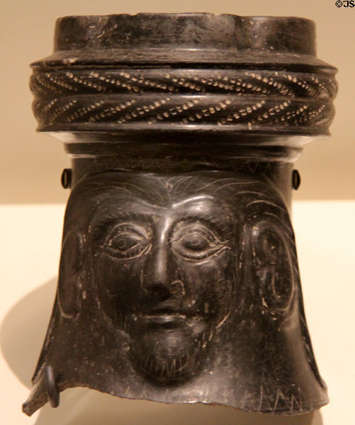 Etruscan black ceramic Bucchero Ware broken-off top of jug with male mask (c550 BCE) at Royal Ontario Museum. Toronto, ON.