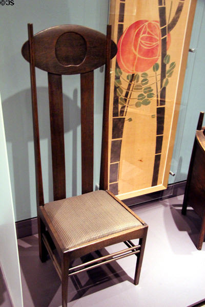 Oak side armchair with horsehair seat (1898) by Charles Rennie Mackintosh originally designed for Miss Cranston`s Argyle Street Tea Rooms of Glasgow beside rose banner (1902) by Mackintosh & Margaret MacDonald for exhibit in Turin, Italy at Royal Ontario Museum. Toronto, ON.