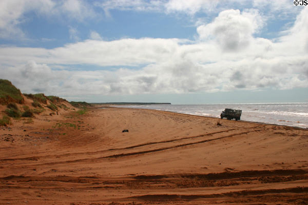 Seaweed truck rolls along red sands on west coast of PEI. PE.