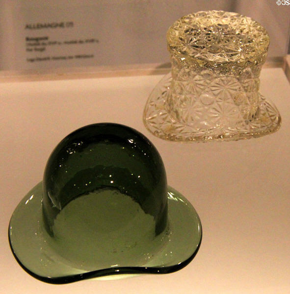 Molded glass top hat (late 19thC) attrib. Burlington Glass Works of Hamilton, ON beside glass bowler hat container (c1900) from England at Montreal Museum of Fine Arts. Montreal, QC.