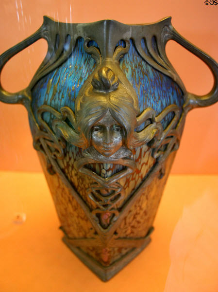 Iridescent glass vessel in pewter frame with female face Art Nouveau decoration (c1900) by Loetz Manuf. of Klostermühle, Austria at Ariana Museum. Geneva, Switzerland.