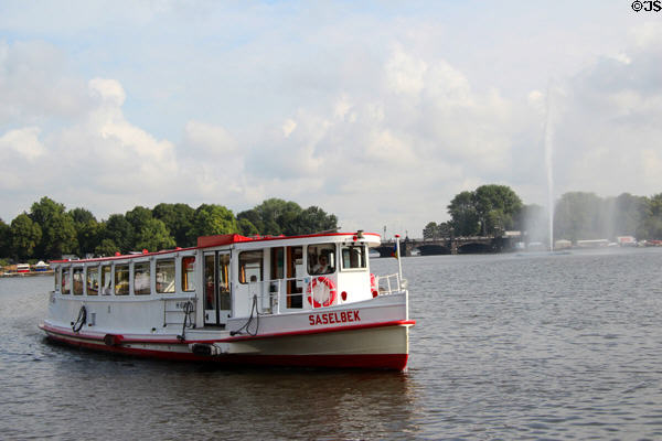 Tour boat passes water spout fountain in Lake Alster. Hamburg, Germany.