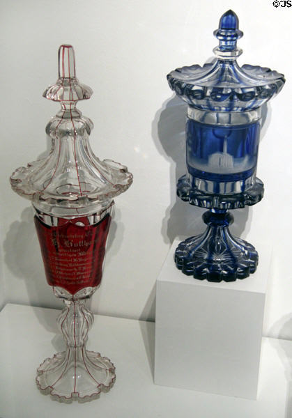 "Birthday Club" lidded glass goblet partly covered in red (1860) & Cup partially covered in blue. In the image field you can see the cut view of the Michaeliskirche with the signature, St. Michaeliskirche at Hamburg History Museum. Hamburg, Germany.