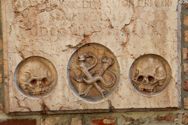 Tombstone with skulls & crossbones mounted on wall of Frauenkirche. Munich, Germany.