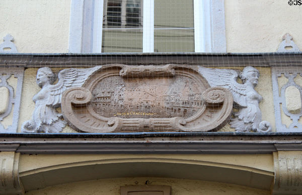 Relief carving (1895) of street scene flanked by sphinxes on Pfisterstaße. Munich, Germany.