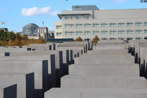 Array of slabs of Monument to Murdered Jews of Europe with Bundestag federal parliament dome beyond. Berlin, Germany.