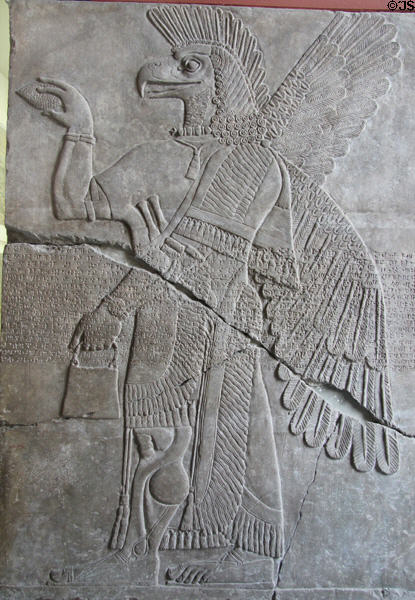 One of pair of Assyrian reliefs (883-859 BCE) of libation induced transition between winged human body with bird head to more normal form with panel over inscribed with cuneiform text at Pergamon Museum. Berlin, Germany.