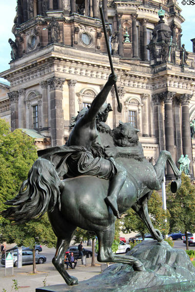 Amazon on Horseback bronze statue (1841) by August Kiss at Altes Museum seen against Berlin Cathedral. Berlin, Germany.