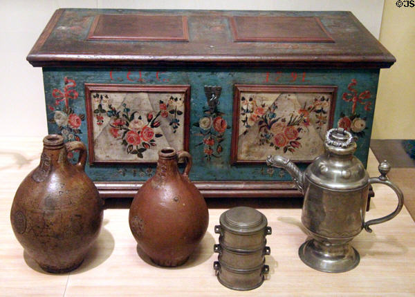 Rustic chest with floral painting (1791) from Saxony or Thüringen; 2 Bartmanns stoneware jugs (18thC) from Rhineland; stacked pewter food boxes (18thC) ; & pewter screw top jug for harvest festival 1793 from Thüringen at German Historical Museum. Berlin, Germany.