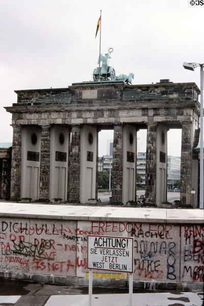 Berlin Wall & Achtung! Sie Verlassen Jetzt West Berlin sign with Brandenberger Gate beyond. Berlin, Germany.