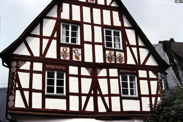 Top floors of half-timbered house (reconstructed 1962) with family crests on facade. Pünderich, Germany.