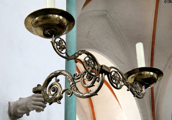 Brass two-candle sconce held by sculpted hand at St Jacob's Church. Lübeck, Germany.