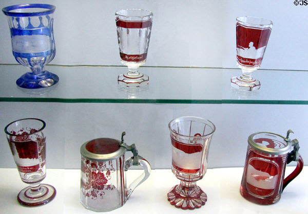 Collection of glass goblets & steins (19thC) where outer colored layer is cut away to form silhouette decorative souvenir pictures of northern Germany at Schleswig Holstein State Museum. Schleswig, Germany.