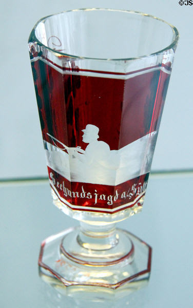 Stemmed two-colored goblet (19thC) where red glass is cut away & etched to show picture of hunting scene at Schleswig Holstein State Museum. Schleswig, Germany.