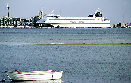 Massive ferry contrasts with a rowboat in Ebeltoft. Denmark.