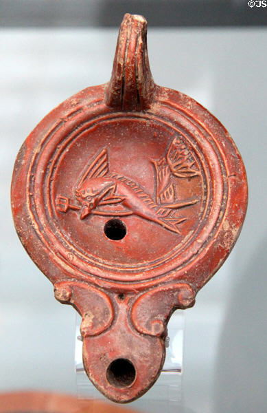 Roman oil lamp with dolphin symbol of sea god (1st-2ndC CE) at Antikensammlungen. Munich, Germany.