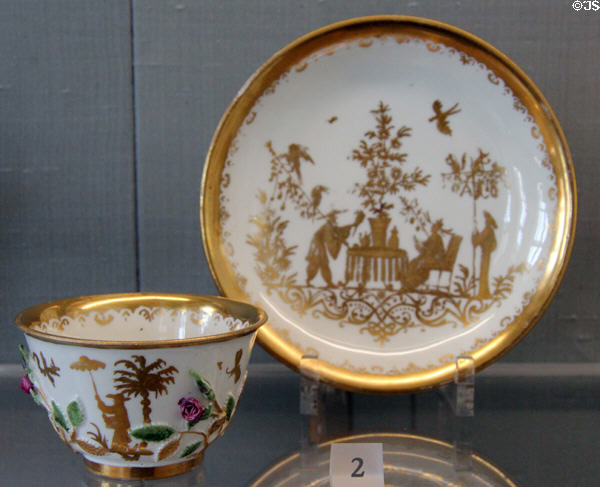 Meissen porcelain chinoiserie cup with applied rose branches painted in gold & enamel colors (after 1726) by Abraham Seutter of Augsburg plus saucer with gilded Chinese scene (1726) at Meissen porcelain museum at Lustheim Palace. Munich, Germany.