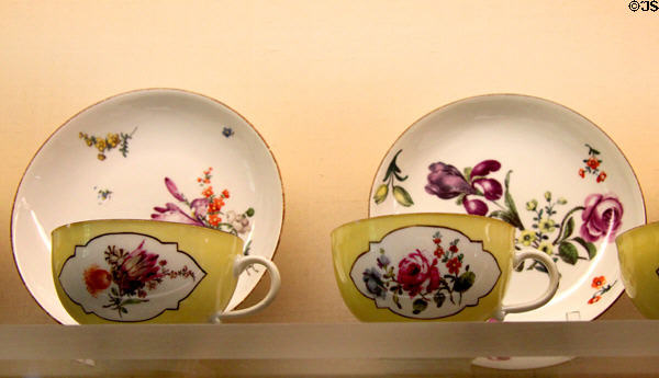 Meissen porcelain yellow cups & saucers (c1750-5) painted with German flowers at Meissen porcelain museum at Lustheim Palace. Munich, Germany.