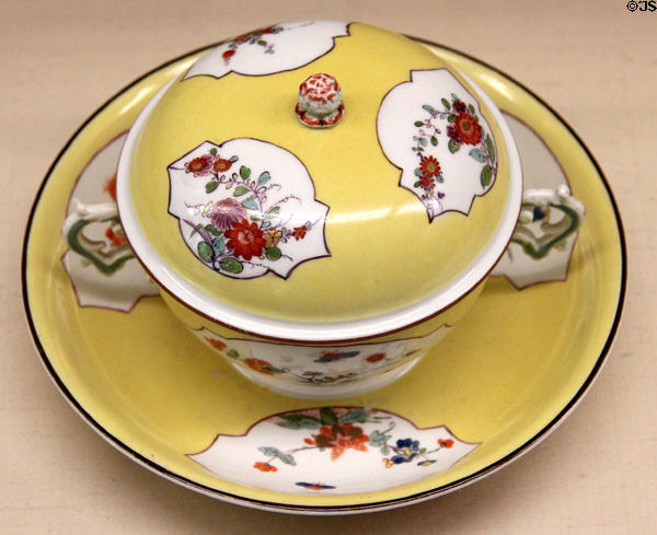 Meissen porcelain yellow covered bouillon cup on saucer (c1730) painted with Indian flowers at Meissen porcelain museum at Lustheim Palace. Munich, Germany.