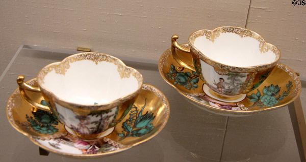 Meissen porcelain quatrefoil-shaped tea cups (c1740) with gold background painted with flowers & Watteau scenes at Meissen porcelain museum at Lustheim Palace. Munich, Germany.