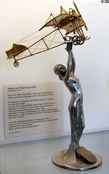 Woman holding monoplane sculpture (c1912) in Jugend stil style to honor German aircraft builder & pilot Gustav Schulze at Deutsches Museum Flugwerft Schleissheim. Munich, Germany.