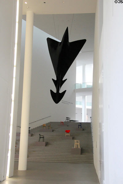 Sculpted arrow-like flying object (2002) by Luigi Colani over chairs displayed on stairs at Pinakothek der Moderne. Munich, Germany.