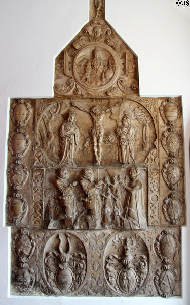 Crucifixion above donors dressed as Medieval knights metal relief surrounded by coats of arms at Maximilian Museum. Augsburg, Germany.