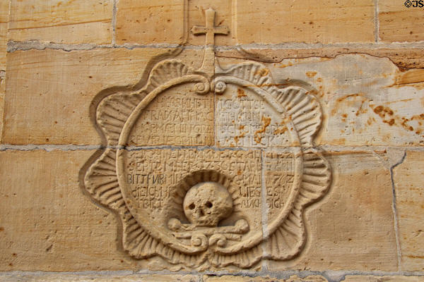 Memorial with skull & crossbones carved in exterior wall at Gößweinstein pilgrimage basilica. Gößweinstein, Germany.