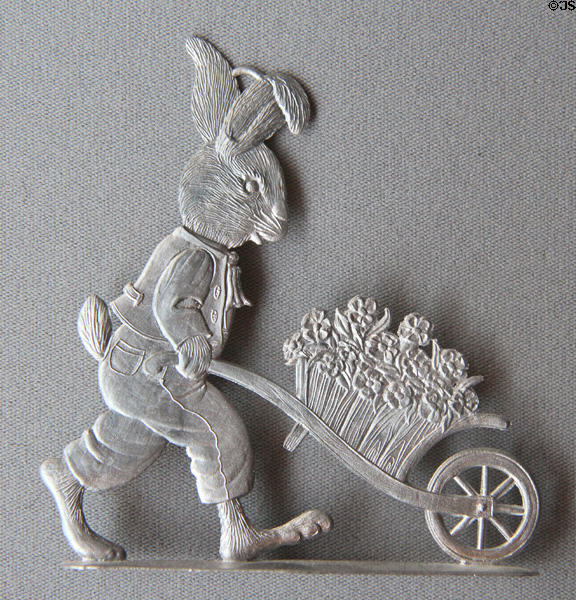 Flat tin unpainted rabbit figure with wheelbarrow of flowers on cast stand from Germany in private collection. Germany.