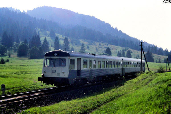 German country train rolling through hills & green valley. Germany.