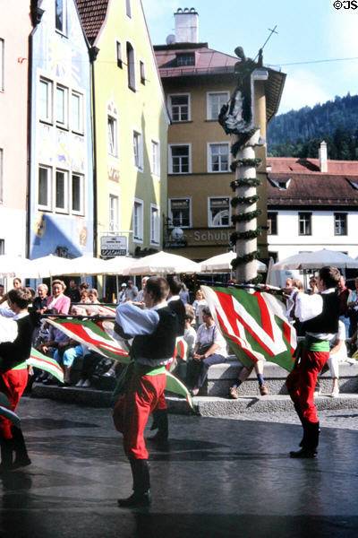 Entertainment on Old Town Square with Stadtbrunnen (fountain) with St Magnus slaying dragon in background. Füssen, Germany.