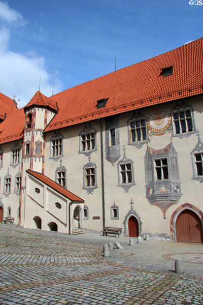 Courtyard & building with covered external staircase, red tiled peaked roof and many painted decorative elements at Hohes Schloss zu Füssen. Füssen, Germany.