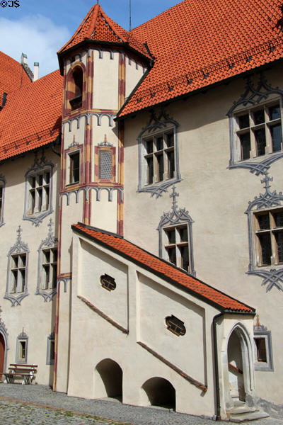 Building with covered external staircase, red tiled peaked roof and many painted decorative elements at Hohes Schloss zu Füssen. Füssen, Germany.