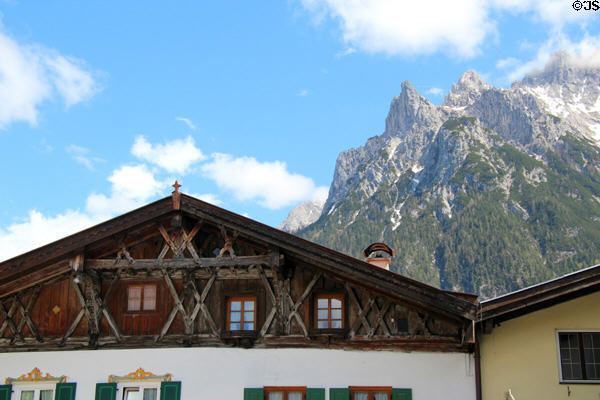 Elaborate woodwork on gable of building with Alps foothills in background. Mittenwald, Germany.