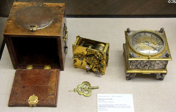 Gold & silver travel clock (1663) by Johann Sayler of Ulm decorated with four continent reliefs with travel case at Ulmer Museum. Ulm, Germany.