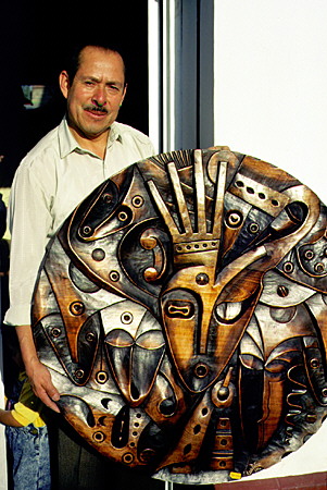 Renowned artist Luis Potosi with his wood carved piece, Circulo Social. Ecuador.