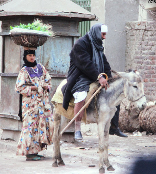 Woman with basket on head & man riding donkey in Giza. Egypt.