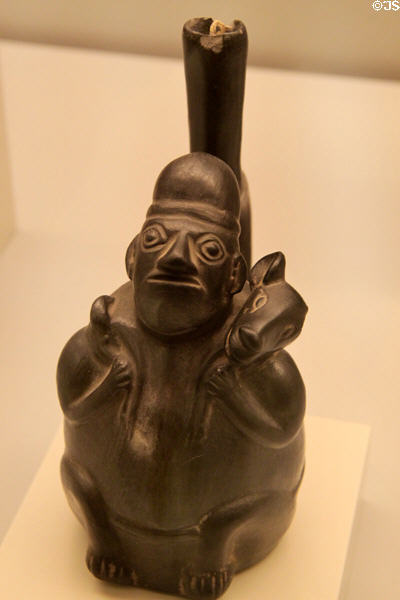 Chimu culture ceramic stirrup-spout bottle with person with dog on shoulders (native dogs were used as source of heat against pains) (1100-1400) from Peru at Museum of America. Madrid, Spain.