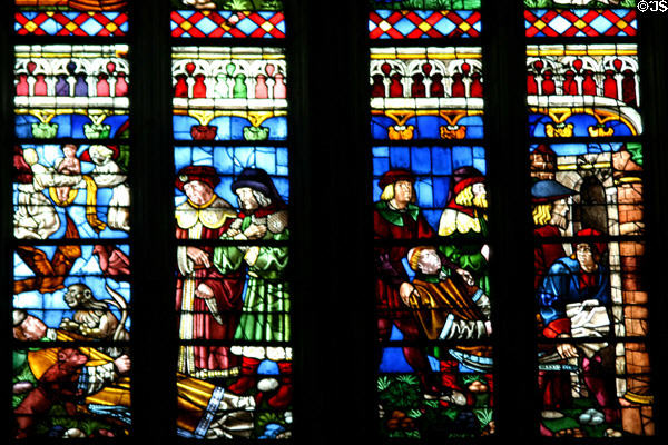 South transept stained glass windows of St Stephen's Cathedral with people & monkeys. Sens, France.
