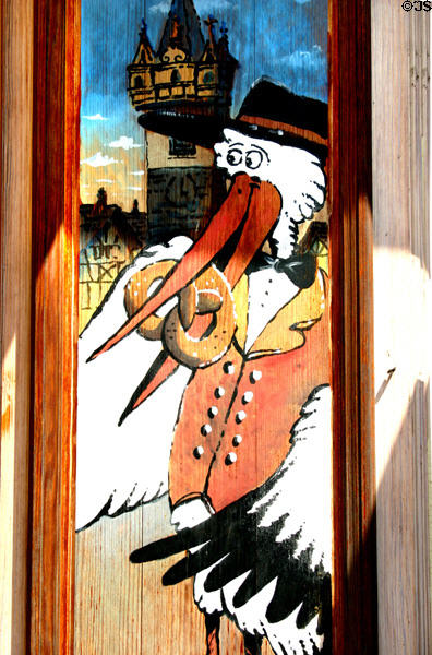 Painted sign with storks eating a pretzel in Alsace. France.