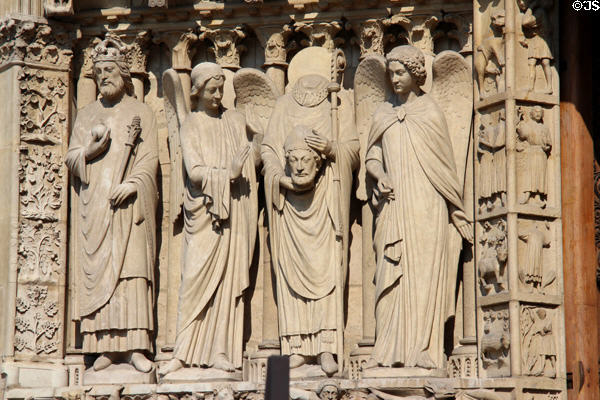 Saints carvings on left portal of Notre Dame Cathedral including St Denis holding head. Paris, France.